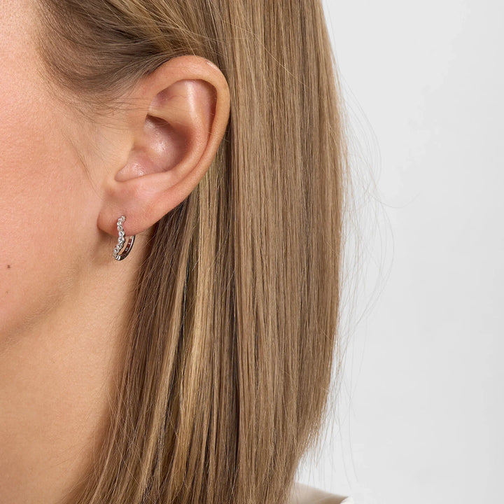 Earring in silver with clear stones, model image shown in the ear from the side