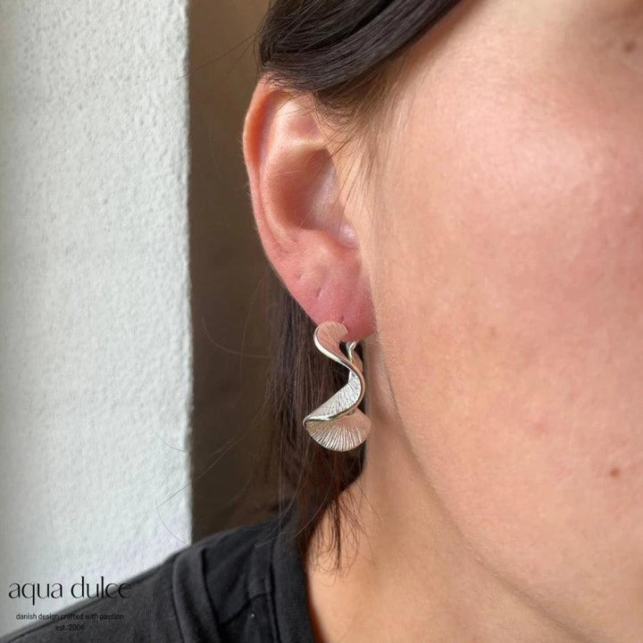 Aqua Dulce Rhumba Hoop Creole Silver shown on ear, elegantly twisted hoop in shiny silver. Model 5099-5099-2