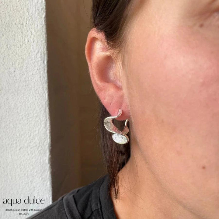 Aqua Dulce Rhumba Medium Hoop in silver appears on ear, elegant wavy design. Model 5319-5319-2
