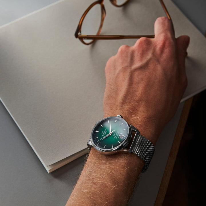 Certina DS-1 Big Date green dial with steel mesh strap worn on wrist at desk. Model C0294261109160