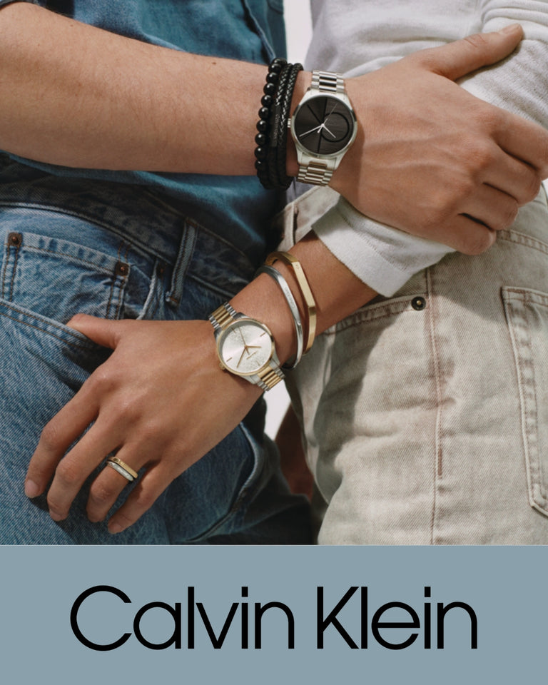 Calvin Klein ure forside, to armbåndsure i sølv med sort og guld urskive, stilfuldt close-up