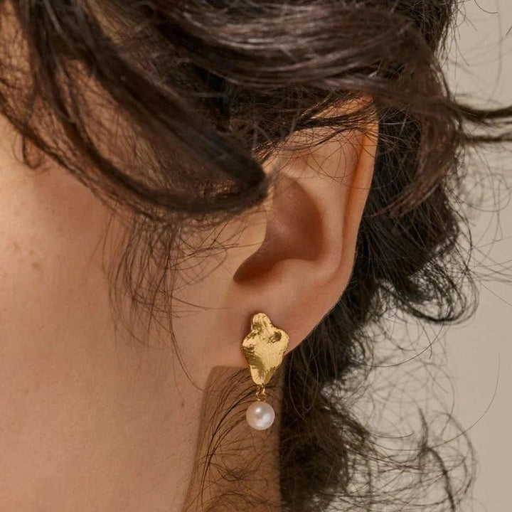 enamel-caia-small-earrings-e374gm appears on ear, matte gold look with hanging white pearl. Model E374GM