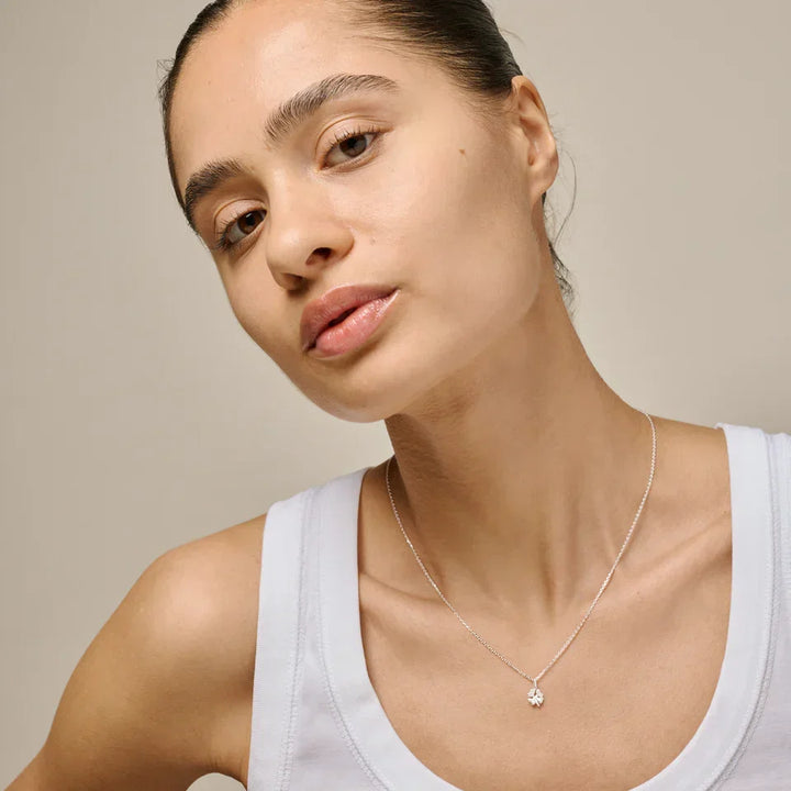 Enamel Four Leaf Clover necklace in silver worn by woman, simple style in neutral light. Model n138sm-2