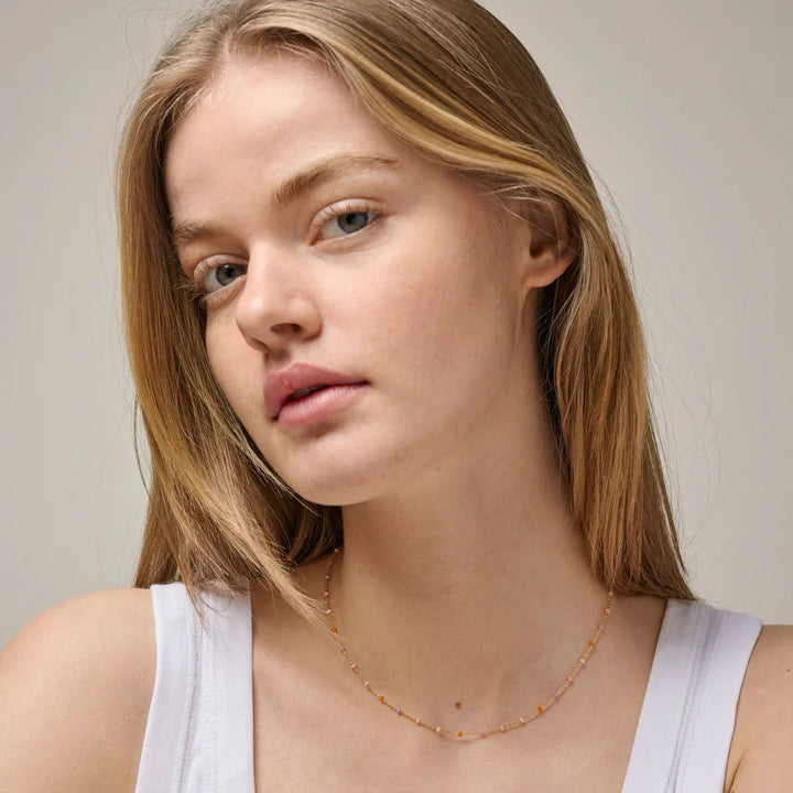 Enamel Lola necklace blush in gold-plated silver shown on model, delicate pink shades shine lightly. Model N55G-BLUSH-2