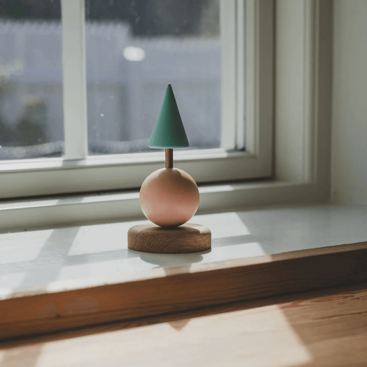 Fablewood Christmas tree Astrid stands on a windowsill, with a green top and a pink ball on a wooden base. Model 1210-1