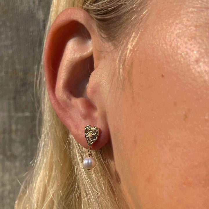 Hultquist Copenhagen Lucia Pearl Heart Earrings in gold with white pearl worn on the ear, Model S08548G-2