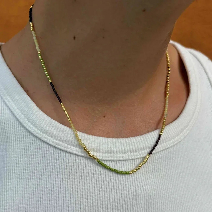 Hultquist Lucky Necklace is shown close to the neck, pearls in green, black and gold. Model S08637G-2