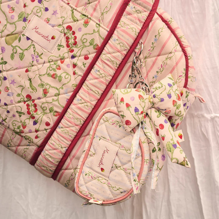 The Moonstone Fabric Bow Key Ring Garden Magic Ivory appears on a quilted bag, floral and pastel. Model 4111-one size