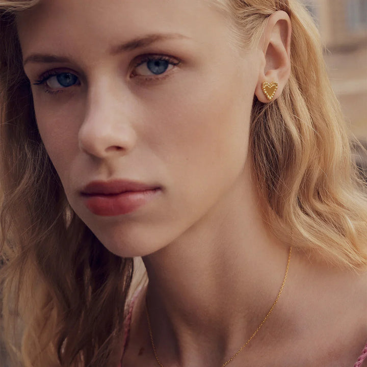 Maanesten Julie gold-plated heart earrings are worn by women, visible detail and golden color. Model 10051a-2