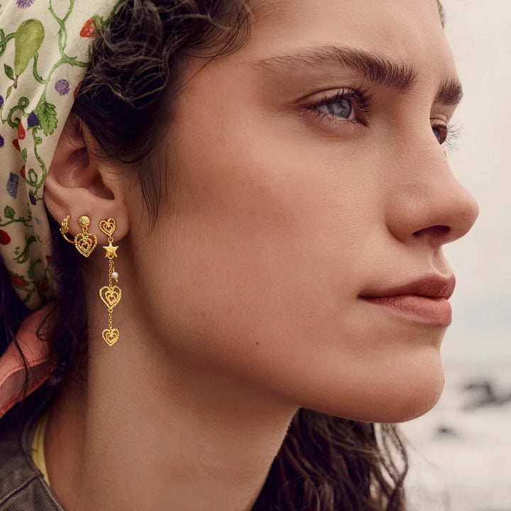 Maanesten Sada gold plated heart earrings shown on model, detailed golden design. Model 10110a