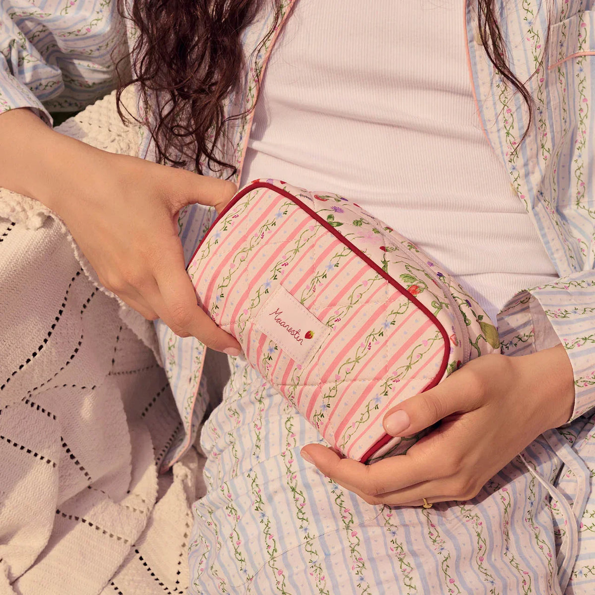 moonstone-stardust-bag-summer-stripes-peach with pink and green striped flower patterns is held in the lap. Model4114-onesize