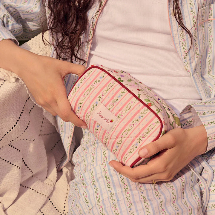 moonstone-stardust-bag-summer-stripes-peach with pink and green striped flower patterns is held in the lap. Model4114-onesize