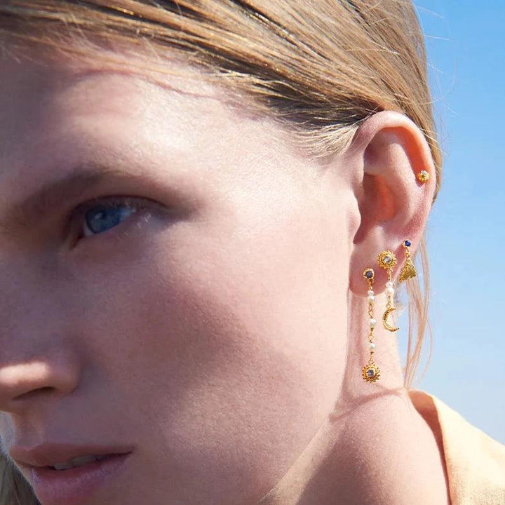 Maanesten Sunniva Earrings gold-plated shown on ear in sunlight, elegant gold pendant and pearl details. Model 9717a-2