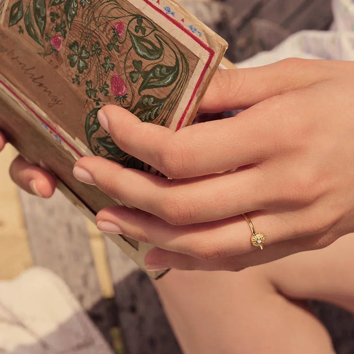 Maanesten Tacita Ring gold-plated seen on hand in sunlight, simple flower ring in gold look, Model 4882a-001