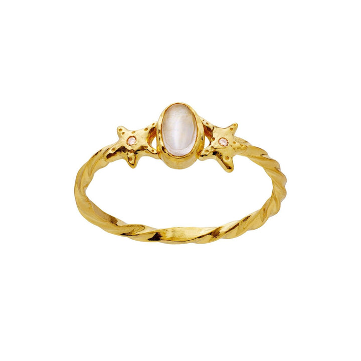 The moonstone Ula Ring gold-plated shows a twisted gold ring with an oval white stone and star-shaped details. Model 4821a-001.