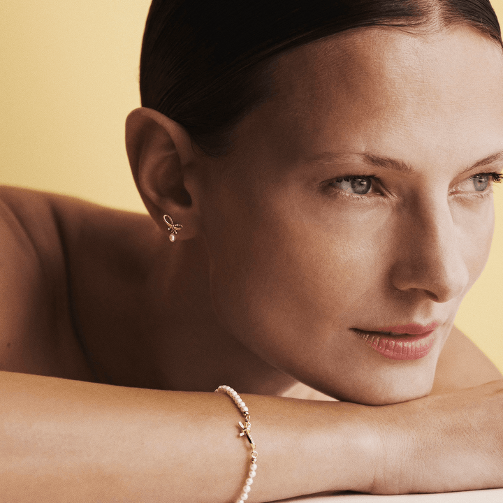 Mads Z Miss Butterfly Bow Pearl bracelet gold and diamonds, worn by woman against light background. Model 1553030-2