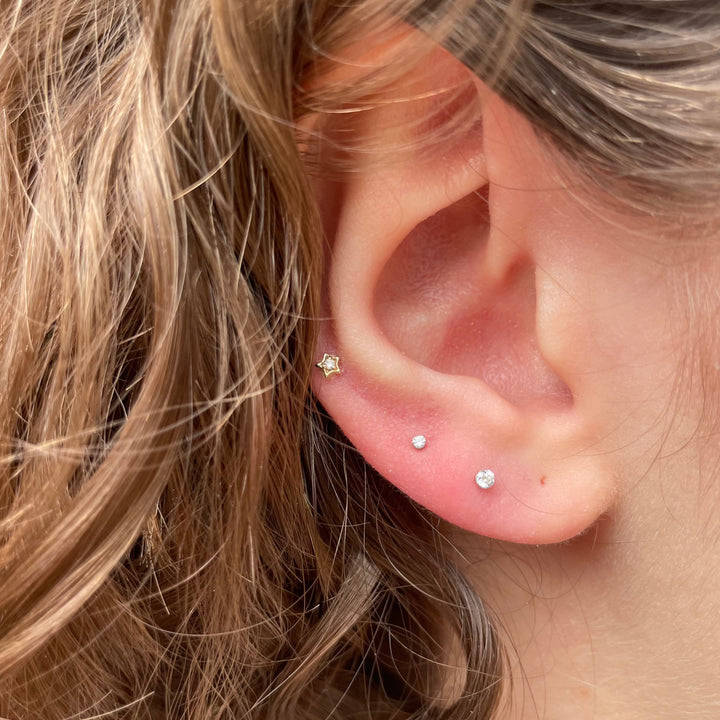 Maria Tash Diamond Solitaire Star XSSTARD YG earring in gold with star design seen in the ear. Model W3-001-2.