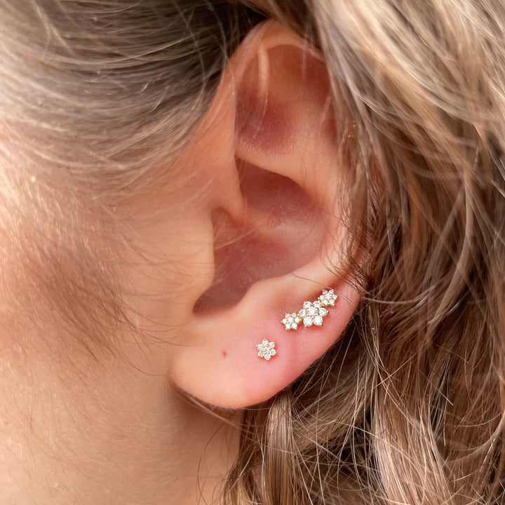 Maria Tash Three Flower Garland Diamond Stud Earring 18k can be seen in the ear, with sparkling diamonds in a floral motif. Model xc3fld-002-2.