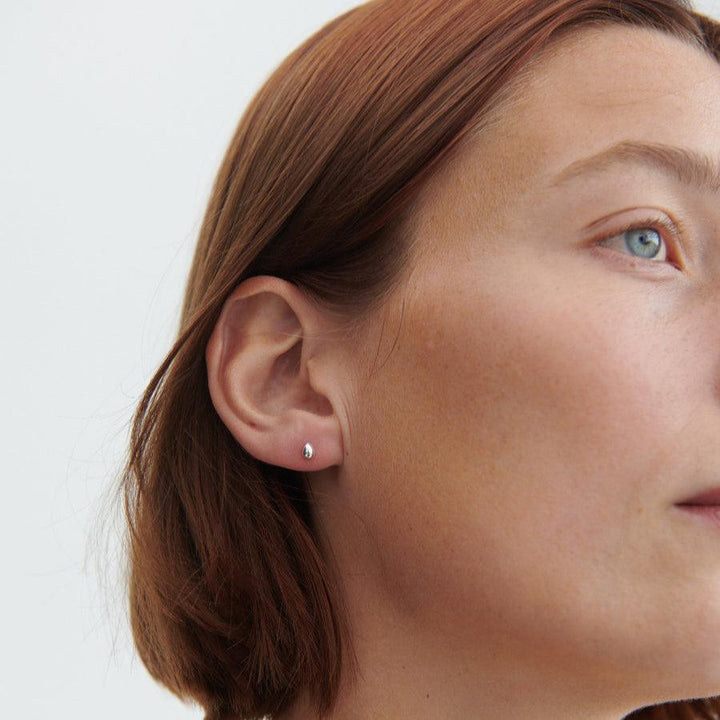 Pernille Corydon Driplet silver ear studs appear on the ear of a woman, simple and elegant style. Model E-305-S-2