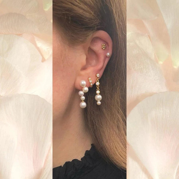 Bella Stud shows elegant earrings in gold with white pearls and stones on ear, Model FW2311-2.