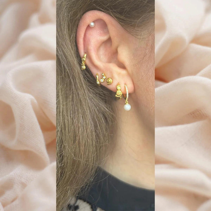 Damona Huggie appears on the ear, gold plated huggie with pearl pendant, elegant and modern. Model FW2401-2