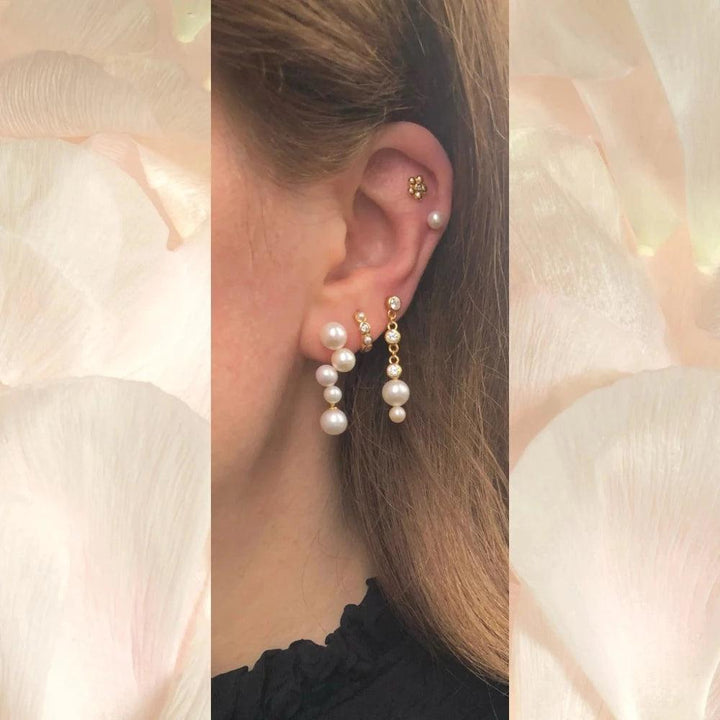 Paloma Stud left shows an ear with elegant gold earring and white pearls in a light environment. Model FW2310-2
