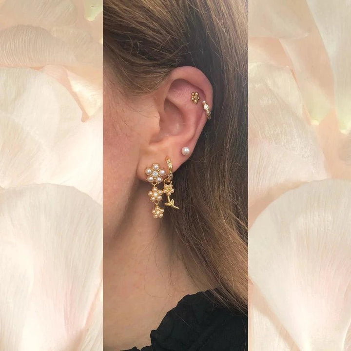 Poppy Stud shows elegant gold colored studs with flowers and pearl details on ear, Model FW2306-2.