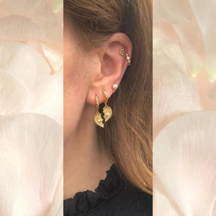 Sola Stud shows golden earrings with twisted design and ear detail, Model FW2312-2