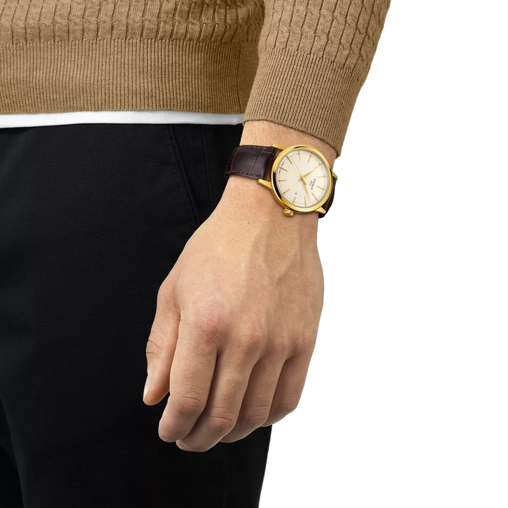 Tissot Classic Dream 42mm gold PVD brown leather strap shows on wrist, elegant classic watch. Model T1294103626100