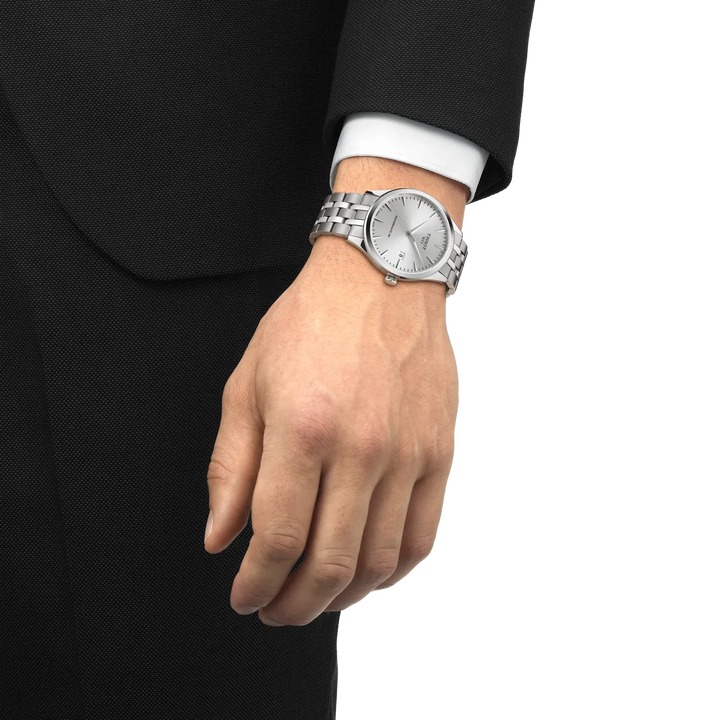 Tissot Classic Dream Powermatic 80 is shown on wrist with steel chain and silver dial. Model T1584071103100