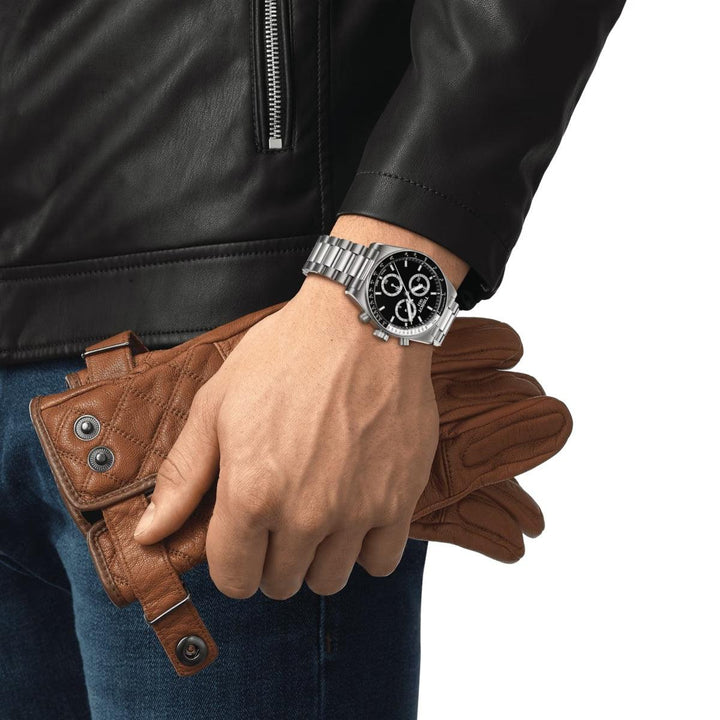Tissot PR516 Chronograph with black dial is seen on wrist with metal strap, wearing black jacket. Model T1494171105100.