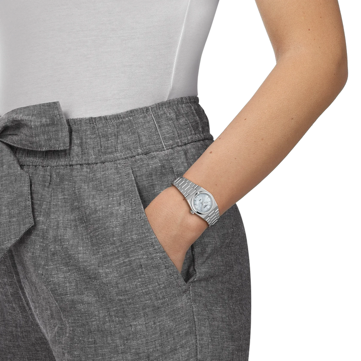 Tissot PRX 25mm mother-of-pearl dial shown on women's hand, elegant steel strap. Model T1370101111100