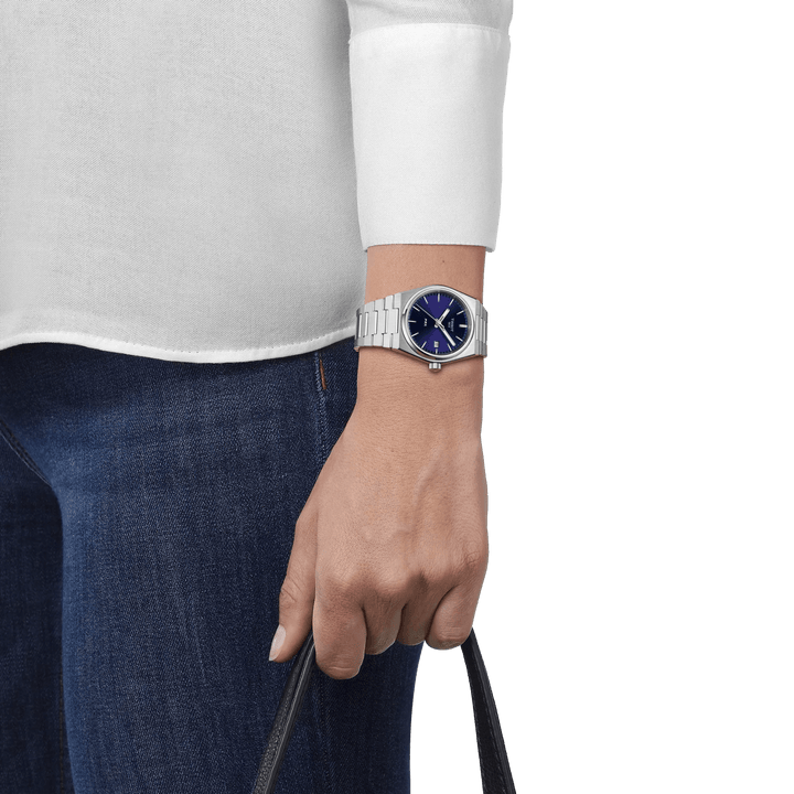 Tissot PRX with blue dial seen on wrist, steel chain and casual style, Model T1372101104100.