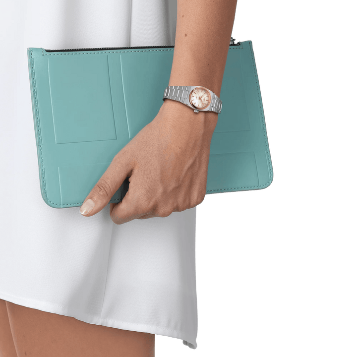 Tissot PRX Rose Gold 25mm can be seen on the wrist, watch in steel and rose gold colour, elegant for a white dress. Model T1370102111100