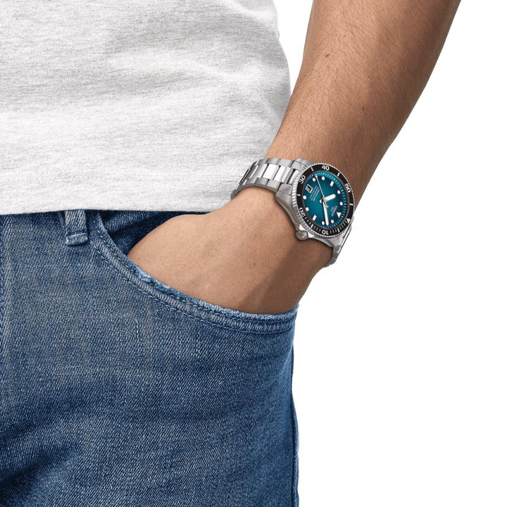 Tissot Seastar 1000 Powermatic 80 turquoise on wrist, steel chain and diver's crown. Model T1208071109100.