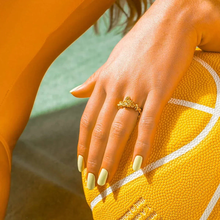 vincent glimmering haze gold-plated ring appears on a woman's hand against orange ball, Model VJ185-URG-001