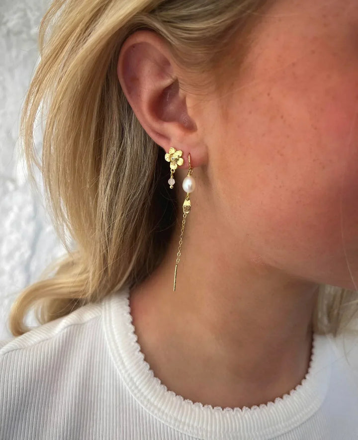 WIOGA Lovis Earrings in gold-plated silver with flower detail and pearl, seen on ear. Model E-9016-GP.