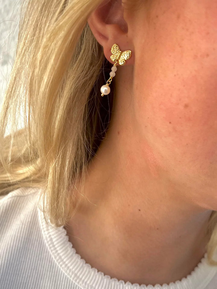 wioga-olivia-ear studs-in-gold-plated-solv-e-9012-gp shown on ear with butterfly shape and pearl, Model E-9012-GP