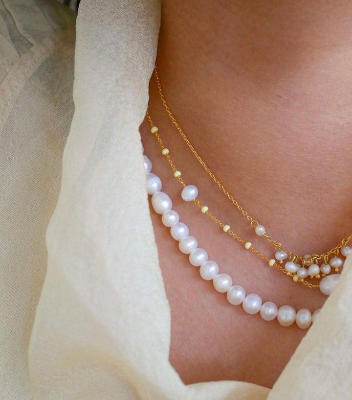 enamel pearlie necklace appears on neck, layered with golden chains and white pearls, Model N67G-N67G-2