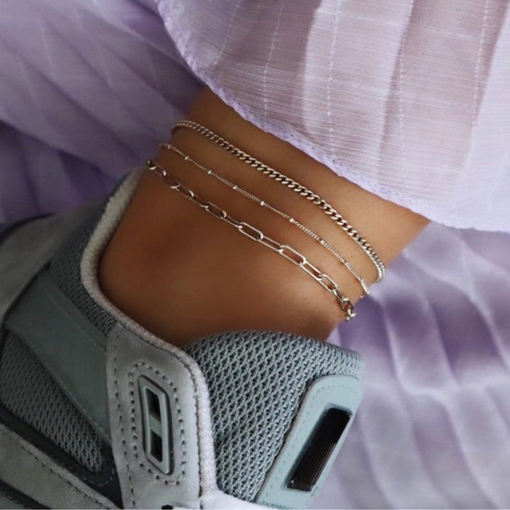 jeberg-jewellery-sophia-solv-anklekaede shows a silver anklet on an ankle with a sneaker and light purple fabric. Model 4550-S-2