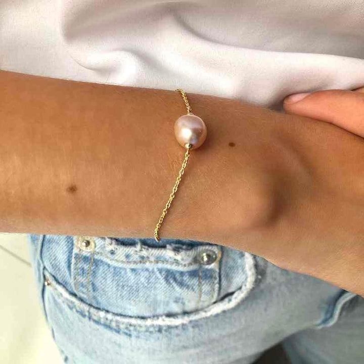 ro copenhagen 18kt joy bracelet with pink baroque is shown around the wrist, elegant gold bracelet with pearl. Model 192l0013-002